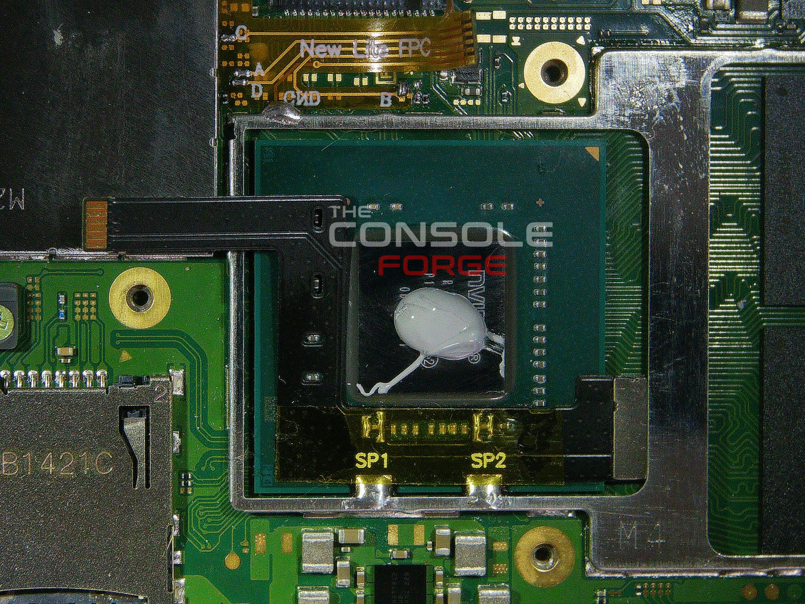 Nintendo Switch Lite APU area with the RP2040 flex cable installed, Kapton tape protecting the soldered connection points, and additional thermal paste applied before reassembling the heatsink and shield.