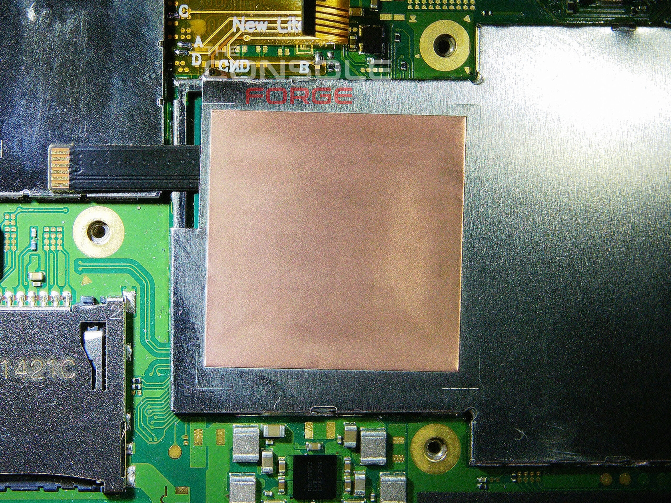 Nintendo Switch Lite motherboard with the modified IHS shield reinstalled over the APU and RP2040 flex cable, showing proper cable routing and shield fitment before final reassembly.