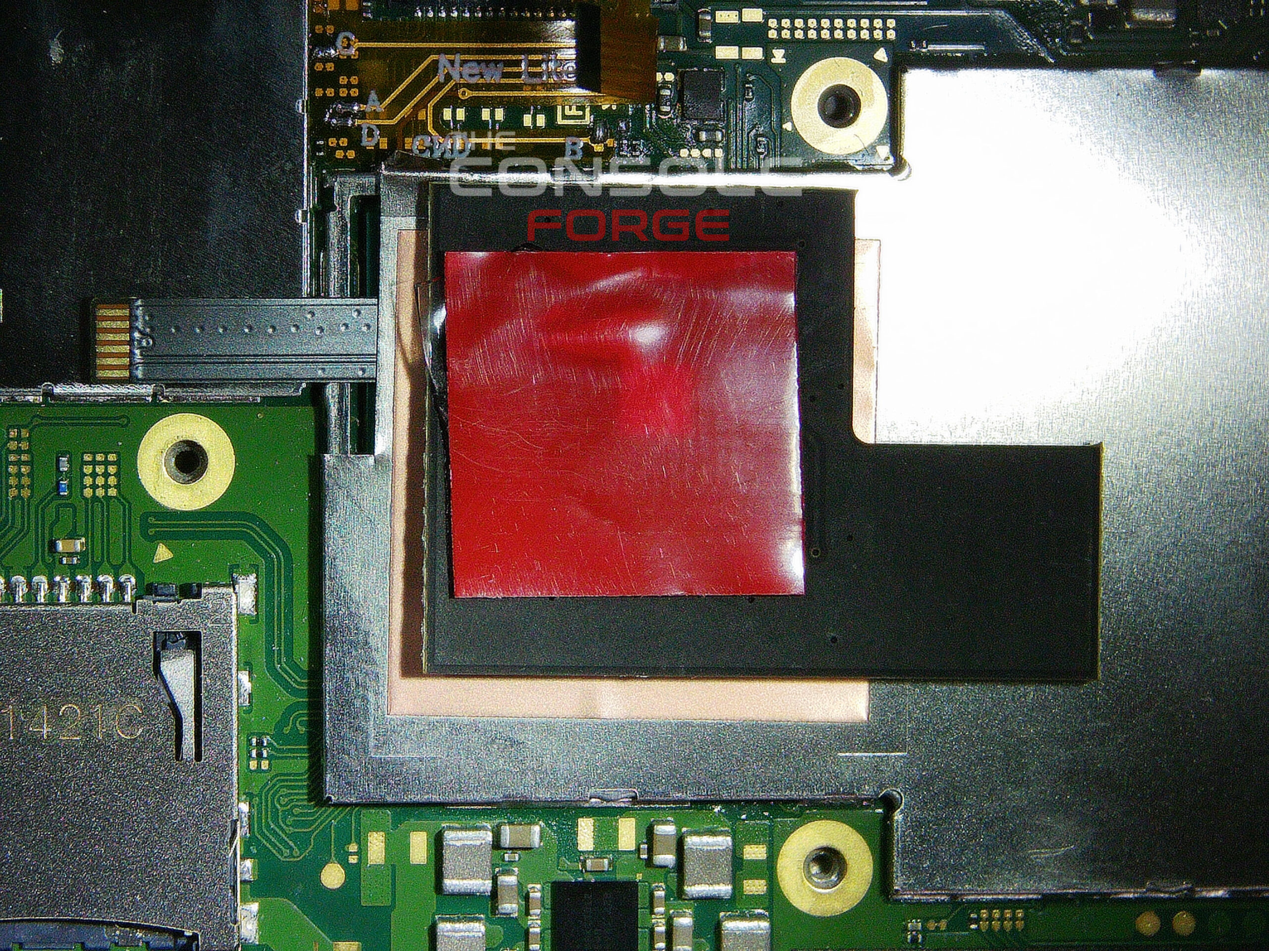 Nintendo Switch Lite motherboard with double-sided adhesive tape applied to the top of the reinstalled IHS shield, preparing the mounting location for the RP2040 modchip.