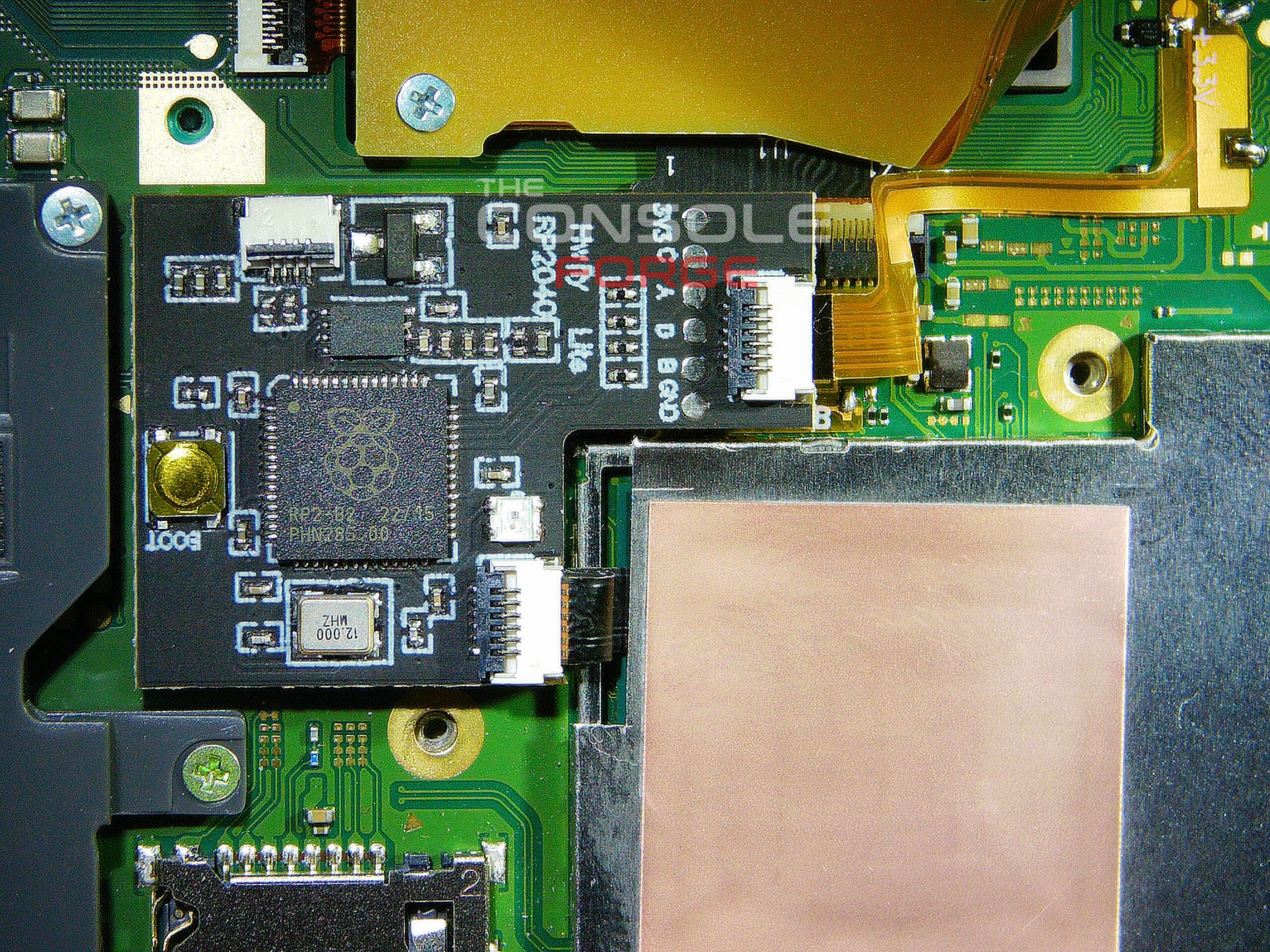 Nintendo Switch Lite motherboard with the RP2040 modchip installed beside the APU shield, connected through dual flex ribbon cables and secured in its final mounted position prior to full console reassembly.